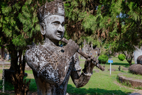 Obraz na płótnie Buddha Park in Vientiane Laos showcases intricate sculpture of flute player among lush greenery w salonie
