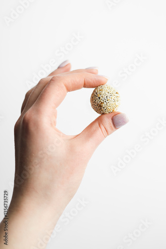Canvas Print Woman holding delicious vegan candy ball with sesame seeds, close up