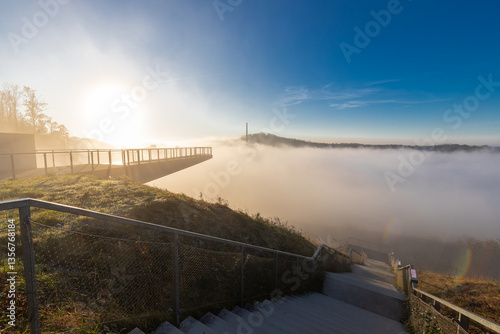 A misty morning on the top of one of the rolling hills in Maastricht where the valley is being blocked by fog, creating a magical atmosphere and idyllic view over the former marl quarry and industry