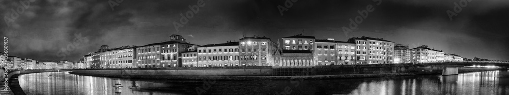 Panoramic view of Pisa buildings along Arno river at night during Luminara - Italy