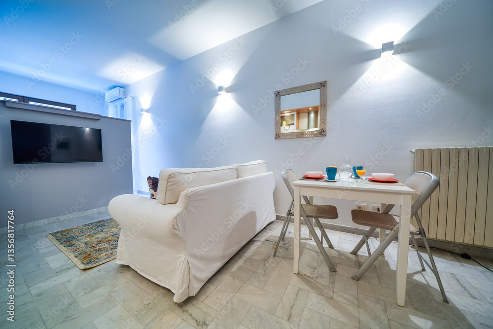 One-room bed and breakfast apartment, white interior design, open space: kitchen with dining table, living room with sofa