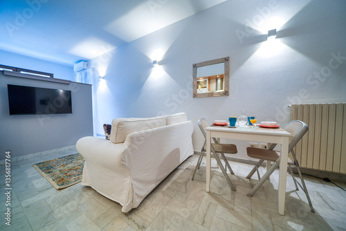 Obraz na płótnie One-room bed and breakfast apartment, white interior design, open space: kitchen with dining table, living room with sofa w salonie