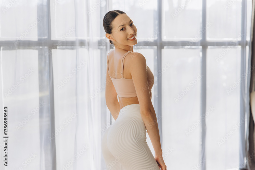 Young woman practicing yoga at home turning back smiling Young woman practicing yoga at home turning back smiling
