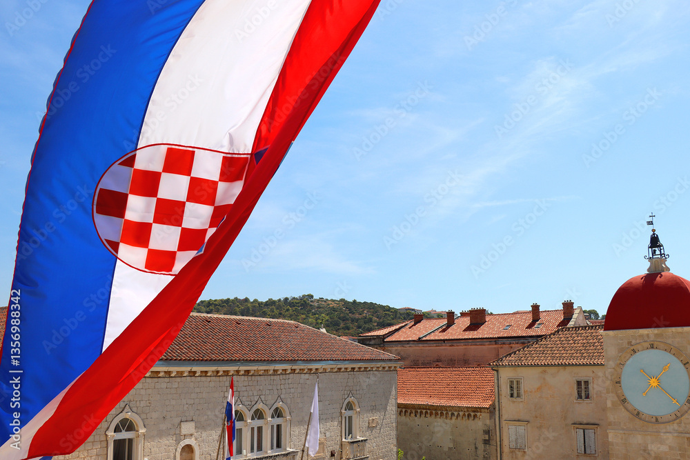 Croatian flag blowing in the wind on the bell tower of The Cathedral of St. Lawrence, landmark in Trogir, Croatia.