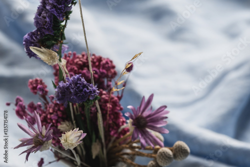 Bouquet of dried flowers close-up on linen light blue tablecloth. Spring delicate floral background, selective focus.