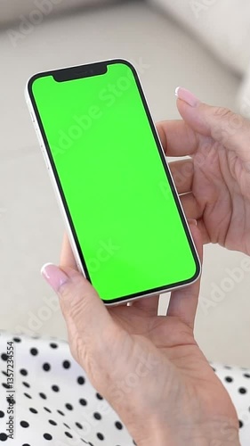 Digital Device with Green Screen Held by Woman on Sofa, Touch screen Engagement, Wireless Tech, Home Relaxation, Interactive Experience, Chroma Key Placeholder for Custom Visual Content.