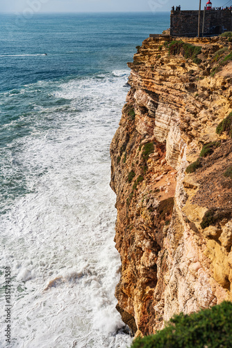 Edge of a rough cliff facing big waves in Nazare, Portugal