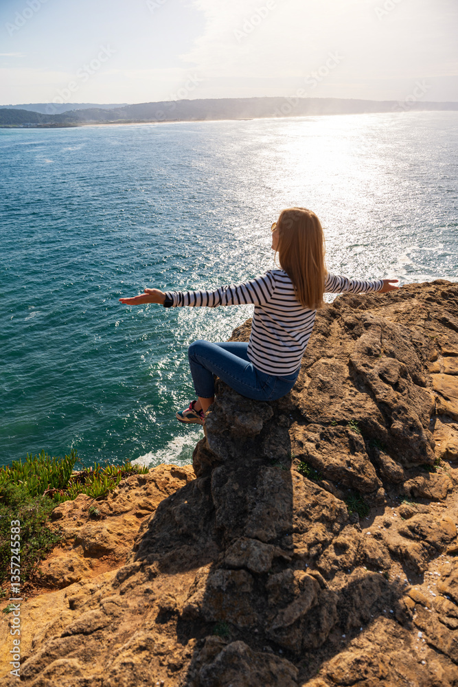Young woman looking at the view of ocean towards Praia do Norte. Nazare, Portugal