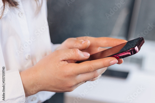Female hands typing a message on a smartphone in a business setting