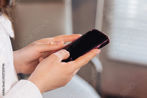 Female hands typing a message on a smartphone in a business setting