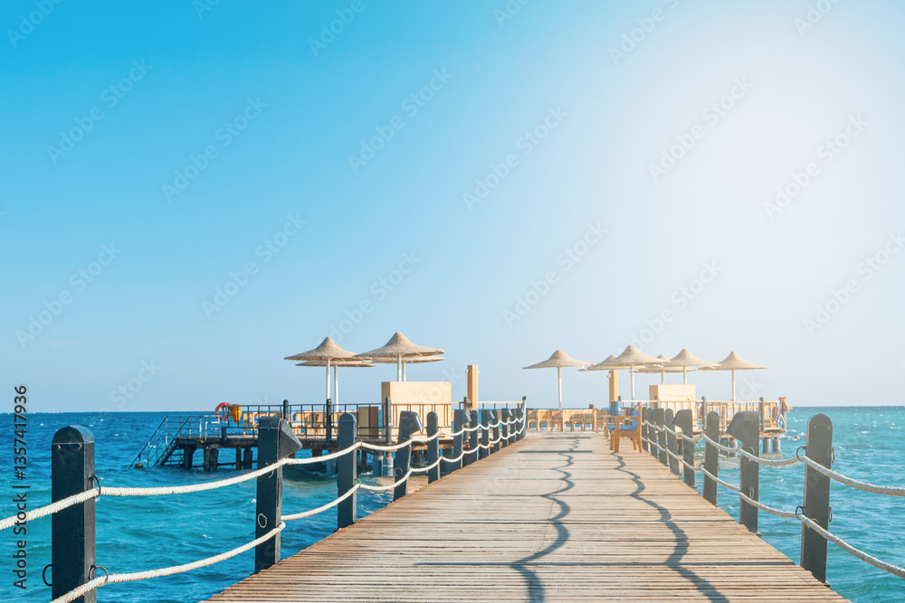 Fototapeta premium Wooden pier on sea stretching into distance beyond horizon on sunny summer day. Vacation and Travel Concept.