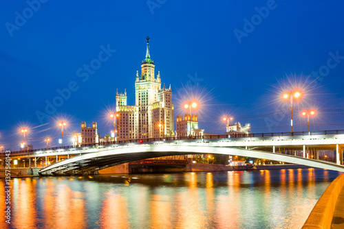 A high-rise building on Kotelnicheskaya embankment and Bolshoy Ustinsky bridge at night. Moscow