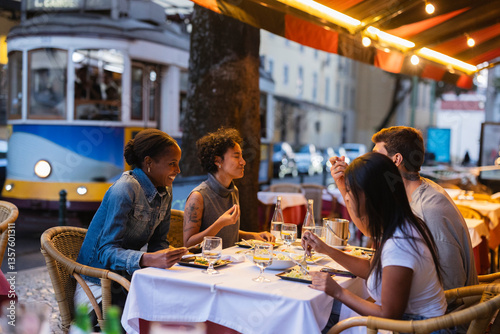 Friends enjoying dinner at outdoor restaurant in lisbon with iconic yellow tram passing by
