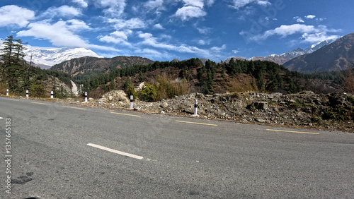 Driving down an empty road with a view of mountains in the distance and cloudy sky. 