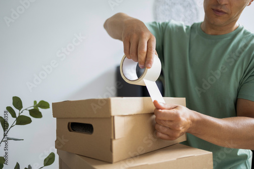 Canvas-taulu Man packing cardboard boxes using packing tape, preparing for house move or stor