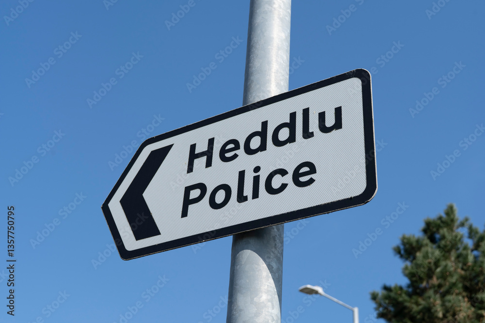Fototapeta premium Roadsign for Police in English and Welsh on a post against a blue sky.