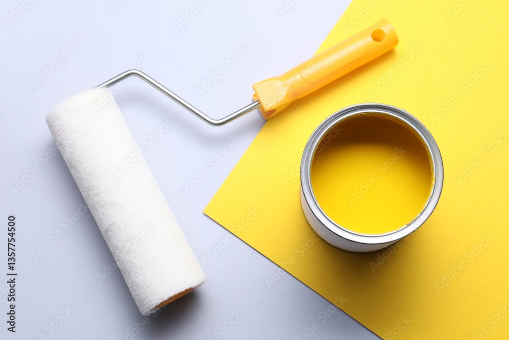 Obraz premium Can of yellow paint and roller on color background, flat lay