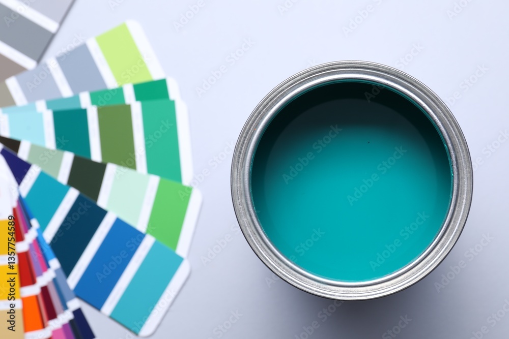 Fototapeta premium Can of bright paint and color palettes on light grey background, flat lay