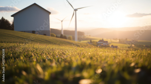 In the rolling hills of rural France, several towering white wind turbines stand against a stunning sunrise. The golden light casts long shadows across the lush green fields