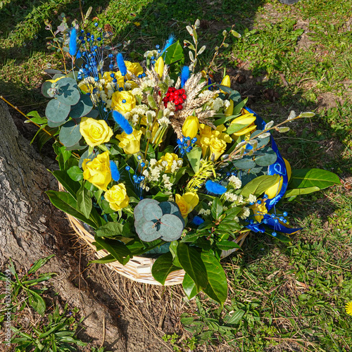 Colorful flower arrangement in a woven basket placed near a tree on a sunny day