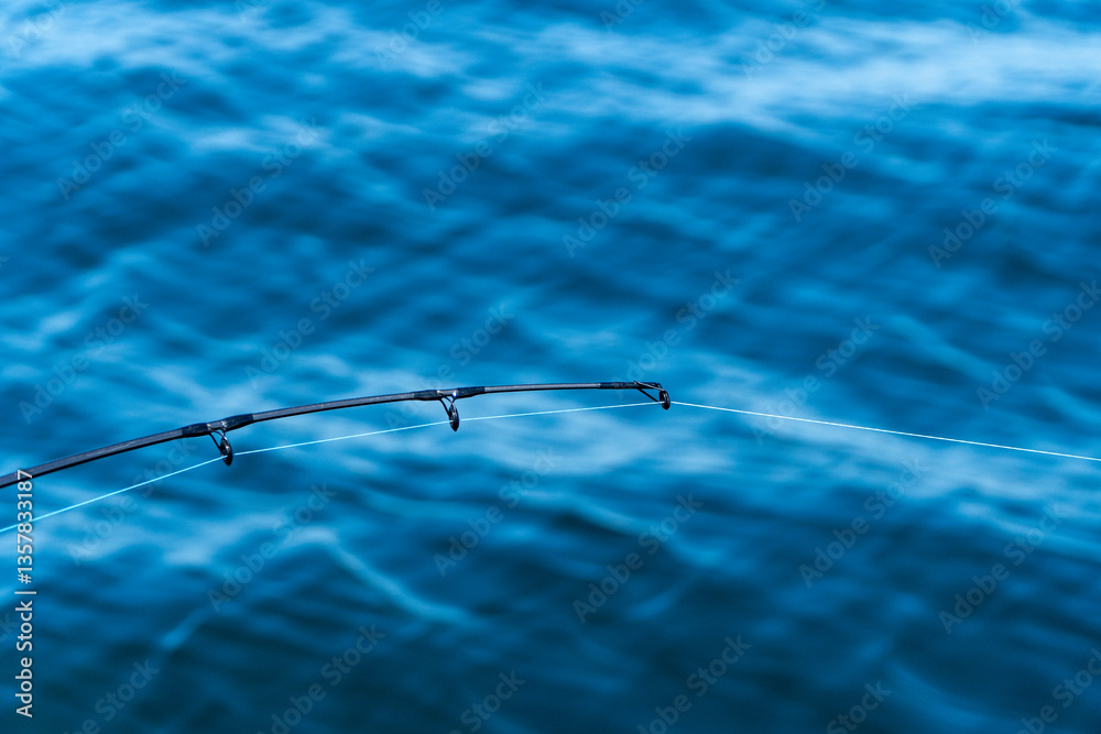 Fishing rod tip over deep blue ocean background