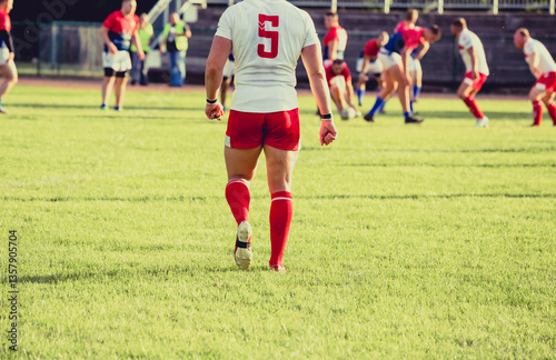 Rugby player walking on the field, and blurred players in the background photo