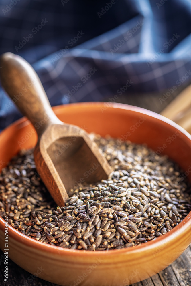 Milk thistle seeds in bowl on wooden table.