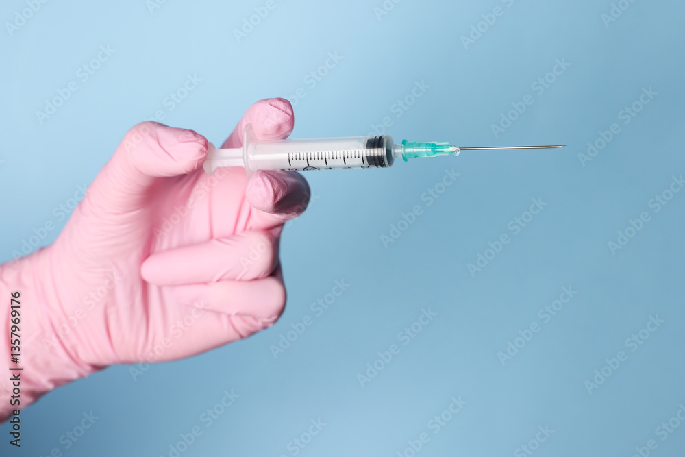 Doctor holding syringe with medication on dusty light blue background, closeup Doctor holding syringe with medication on dusty light blue background, closeup