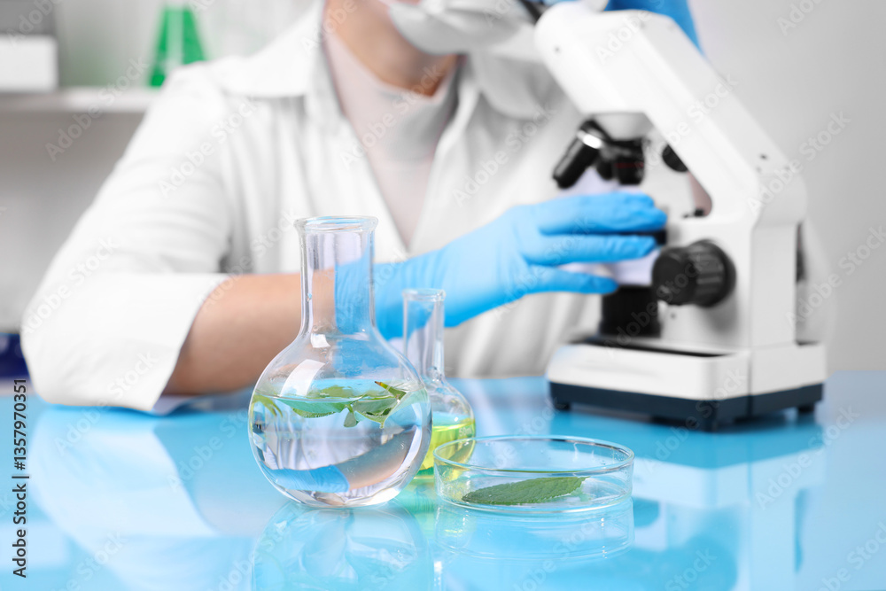 Biochemistry. Scientist working with plants and reagents at blue table in laboratory, closeup Biochemistry. Scientist working with plants and reagents at blue table in laboratory, closeup