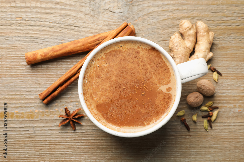 Aromatic Masala tea in cup and spices on wooden table, flat lay