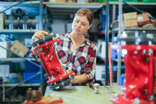 Young caucasian woman mechanic assembling plumbing fixture in workshop.