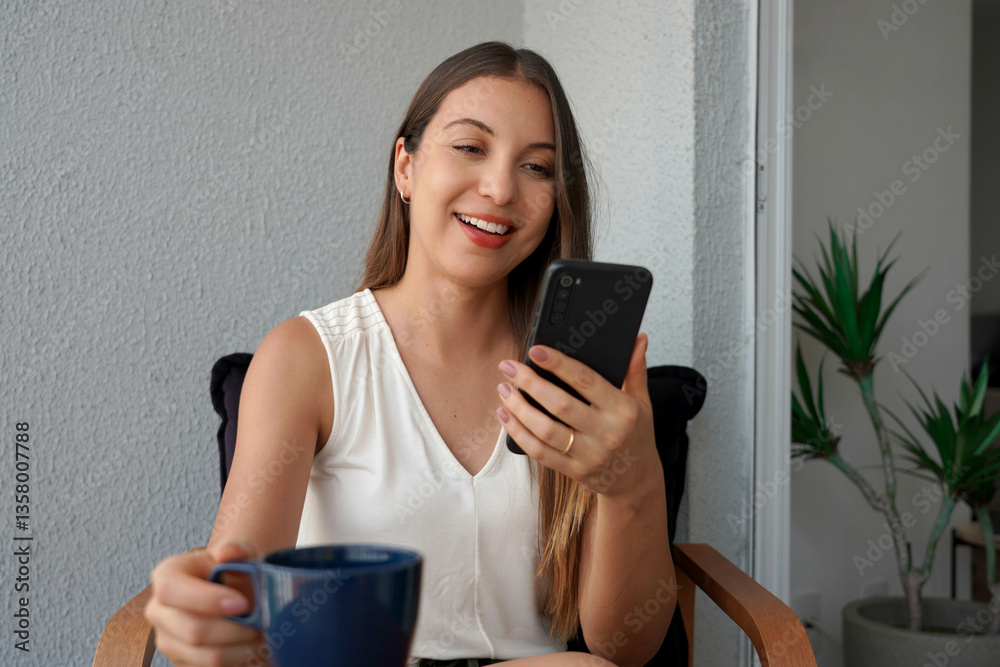 Multi-ethnic business woman using smartphone for video call on her apartment balcony in the morning