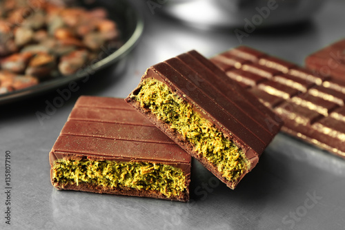 Photography Pieces of tasty Dubai chocolate with pistachios and knafeh on grey table, closeu