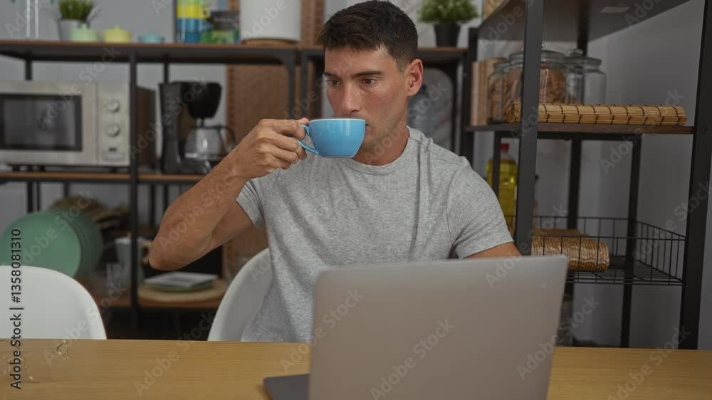 Man in office drinking coffee while working on a laptop showing a modern workplace with various kitchen appliances and decor in the background. Man in office drinking coffee while working on a laptop showing a modern workplace with various kitchen appliances and decor in the background.