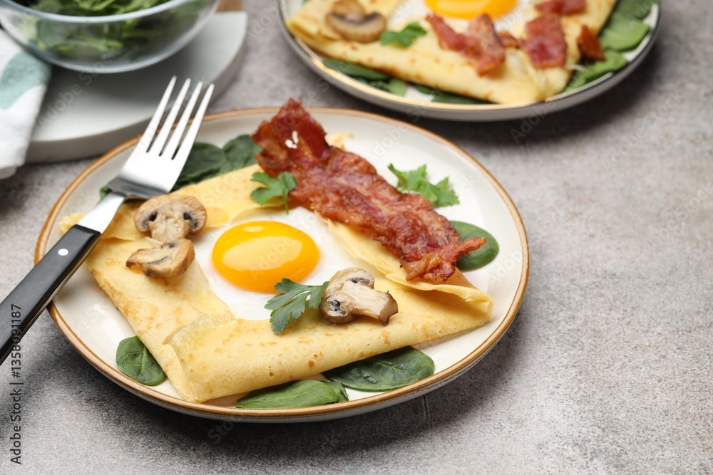 Delicious crepes with eggs, bacon and mushrooms served on grey table, closeup. Breton galette Delicious crepes with eggs, bacon and mushrooms served on grey table, closeup. Breton galette