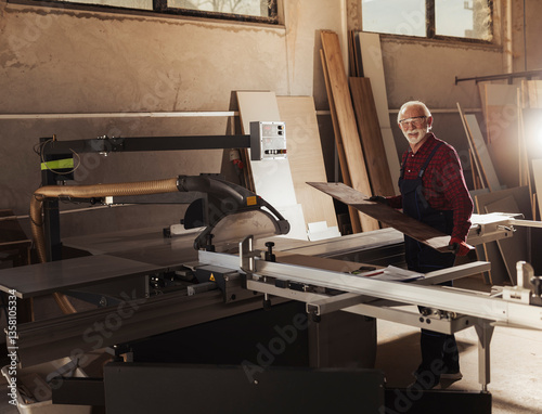 Portrait of elderly man working with a saw in a woodshop photo