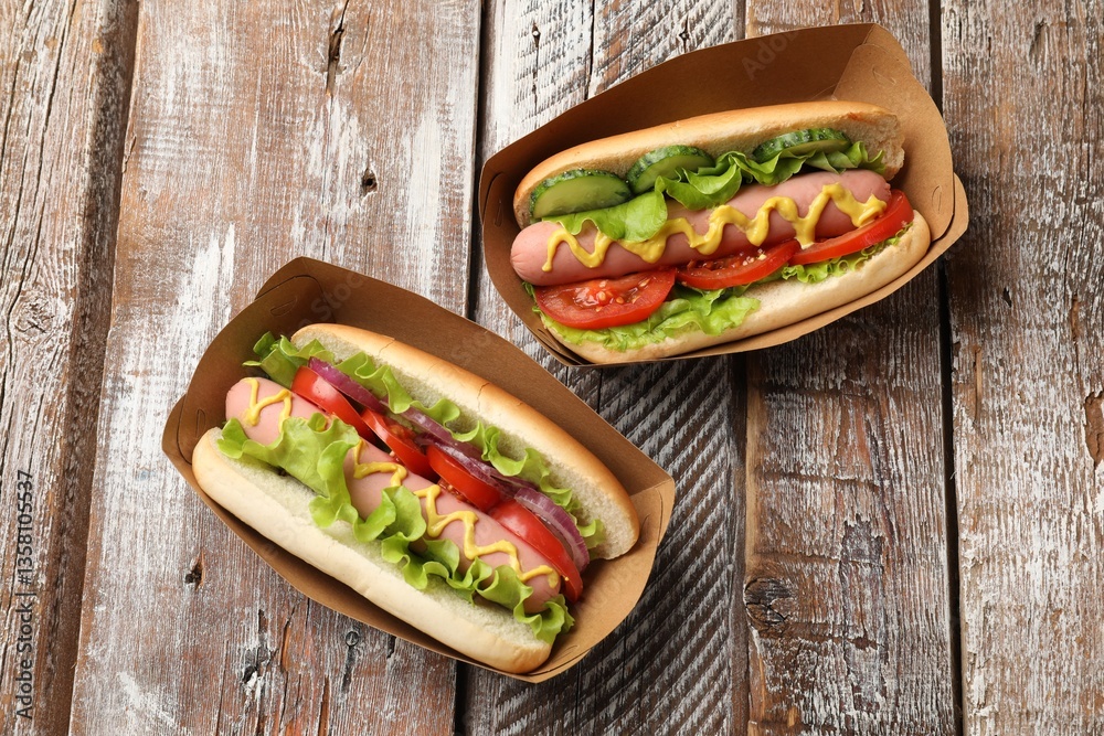 Fototapeta premium Tasty hot dogs on wooden table, flat lay