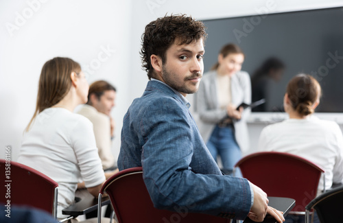 Young smiling man attending lecture in university