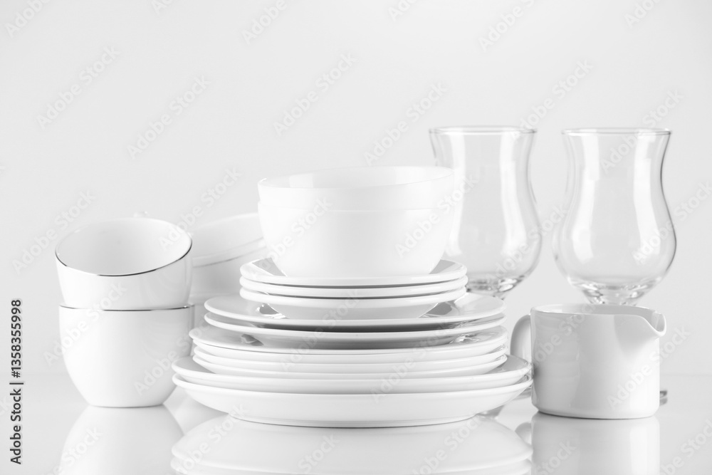 Fototapeta premium Different clean dishware and glasses on light background