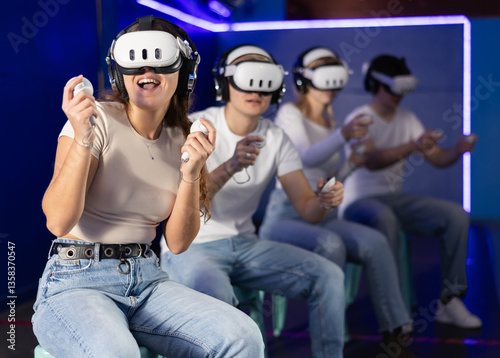 In dark hall of entertainment center, young guys and girls talking about spending time in virtual game. Non-existent reality, immersion in fantastic world of game
