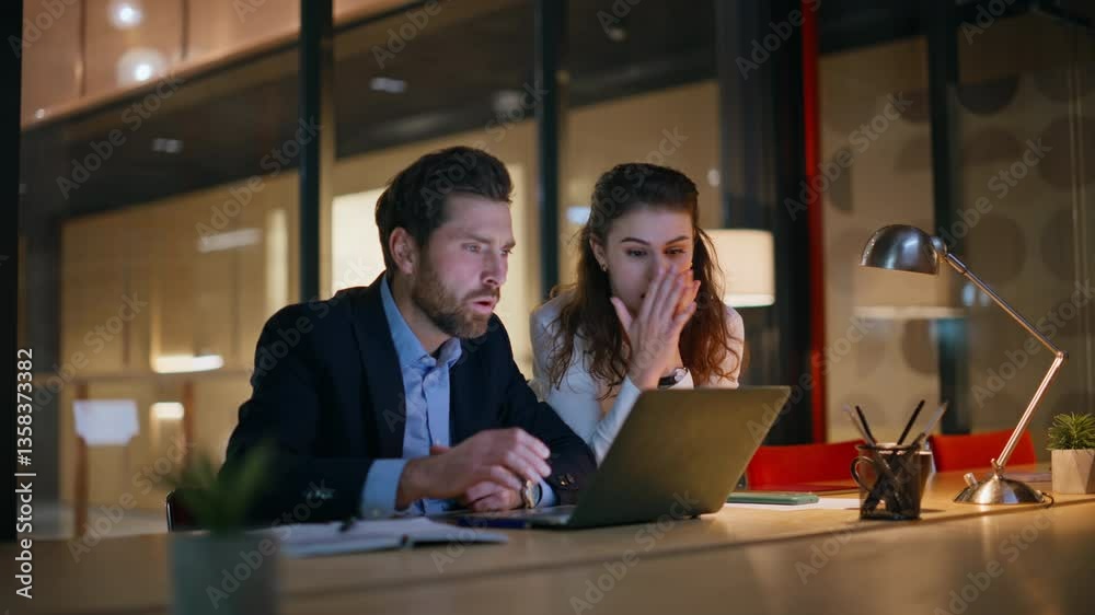 Nervous coworkers closing laptop frustrated project failure at dark office.