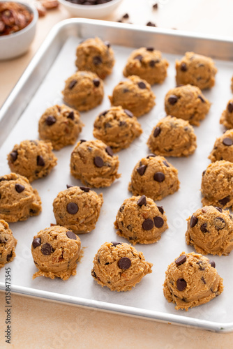Chocolate chip cookies with pecan nuts, cookie dough ready on a baking sheet