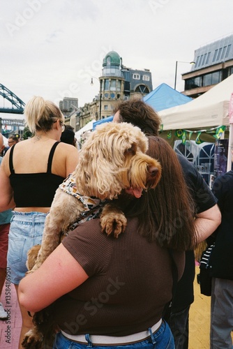 Dog with tongue out being carried through busy quayside market in Newcastle - candid taken on film 