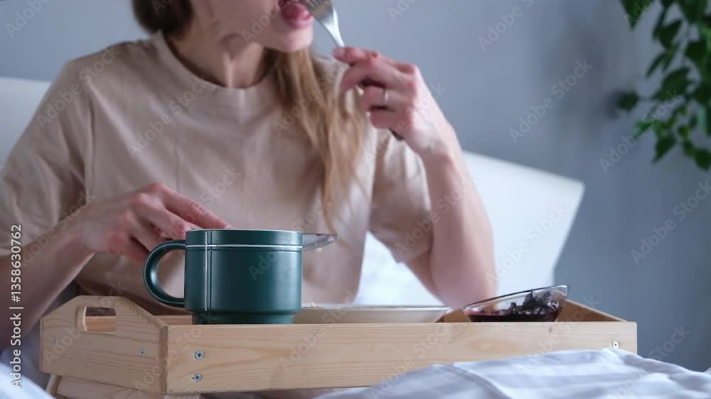 young Caucasian woman having breakfast in bed at home