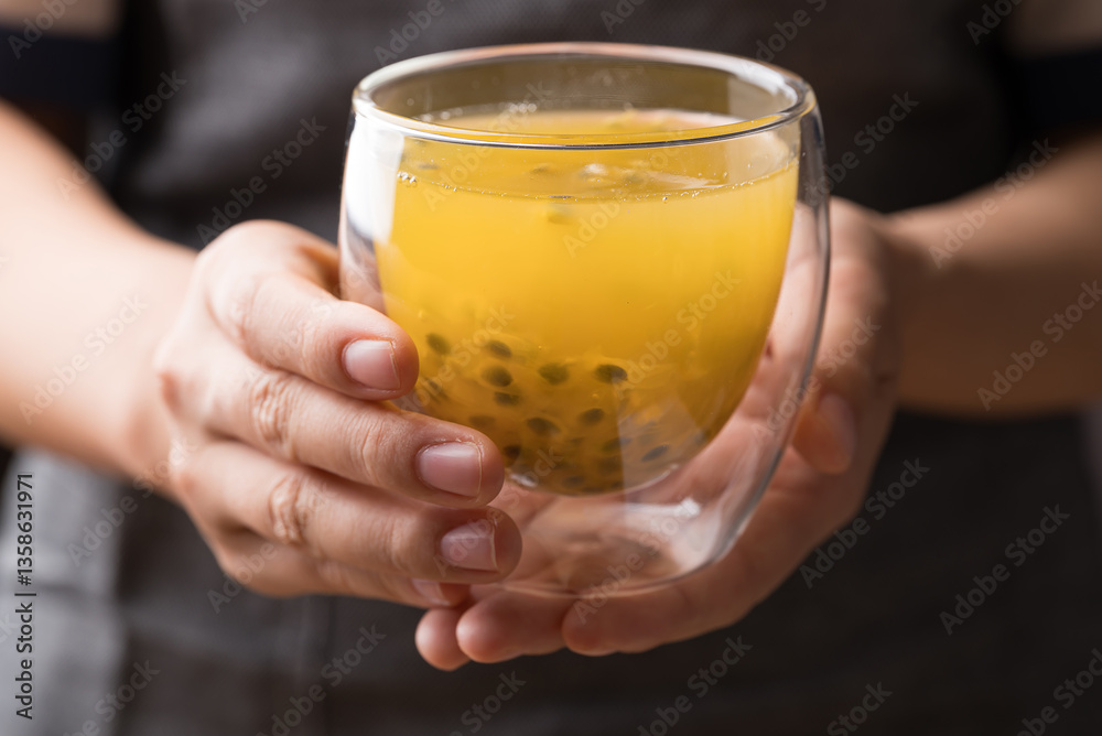 Glass of passion fruit juice holding by hand, Healthy drink Glass of passion fruit juice holding by hand, Healthy drink