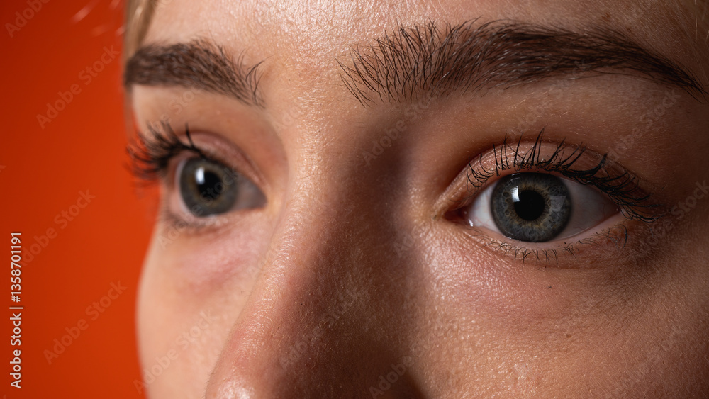 Naklejka premium Extreme close-up of a woman's blue-gray eyes with long eyelashes and natural skin texture. Beautiful eye details, clear gaze and sharp focus on facial features, selective focus