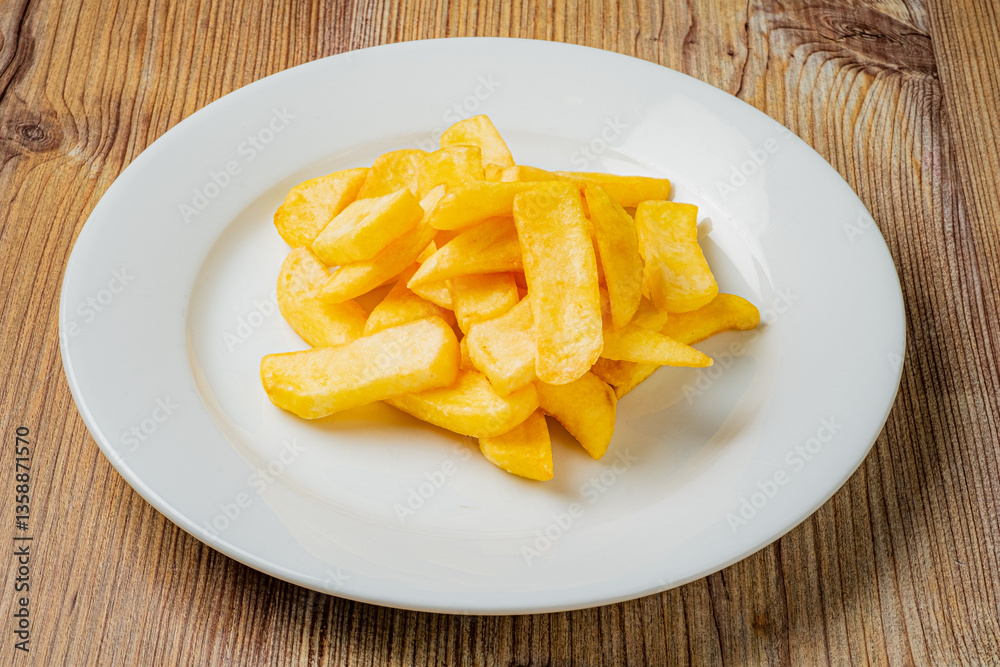 Delicious, golden potato fries piled high on a white plate against a warm, inviting wood backdrop Delicious, golden potato fries piled high on a white plate against a warm, inviting wood backdrop
