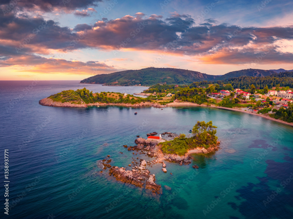Picturesque evening scene of Saint Nicholas church and Ag. Nikolaos village. Great sunset on Euboea island, Greece, Europe. Amazing summer seascape of Aegean sea. Traveling concept background.