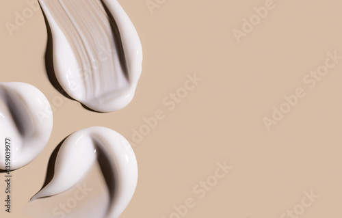 creamy texture of cosmetic samples on a pastel beige background