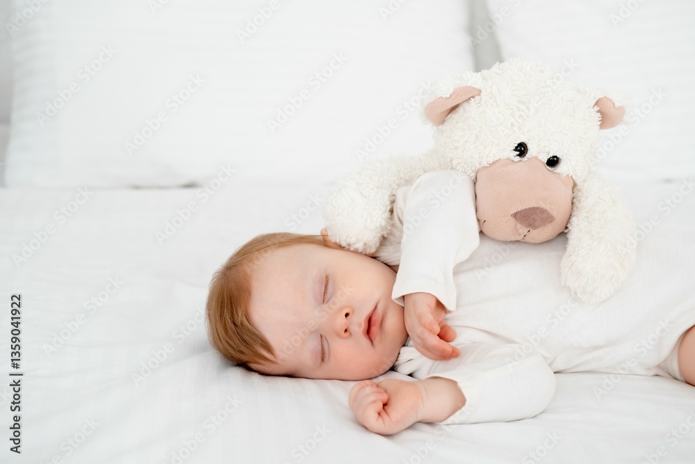 A baby boy sleeps under a blanket in a white bodysuit on the bed with his hand folded under his cheek and holding a soft toy, a sweet healthy baby sleep at home A baby boy sleeps under a blanket in a white bodysuit on the bed with his hand folded under his cheek and holding a soft toy, a sweet healthy baby sleep at home